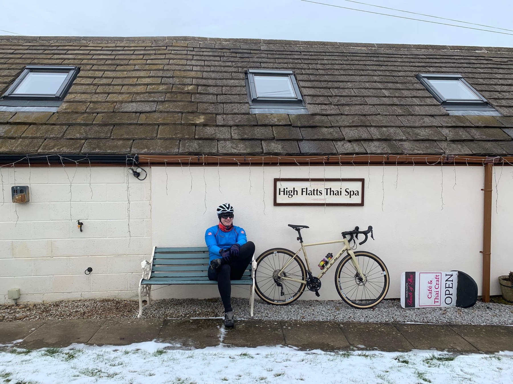 Shea sitting on a bench beside his bike outside High Flatts Thai Spa