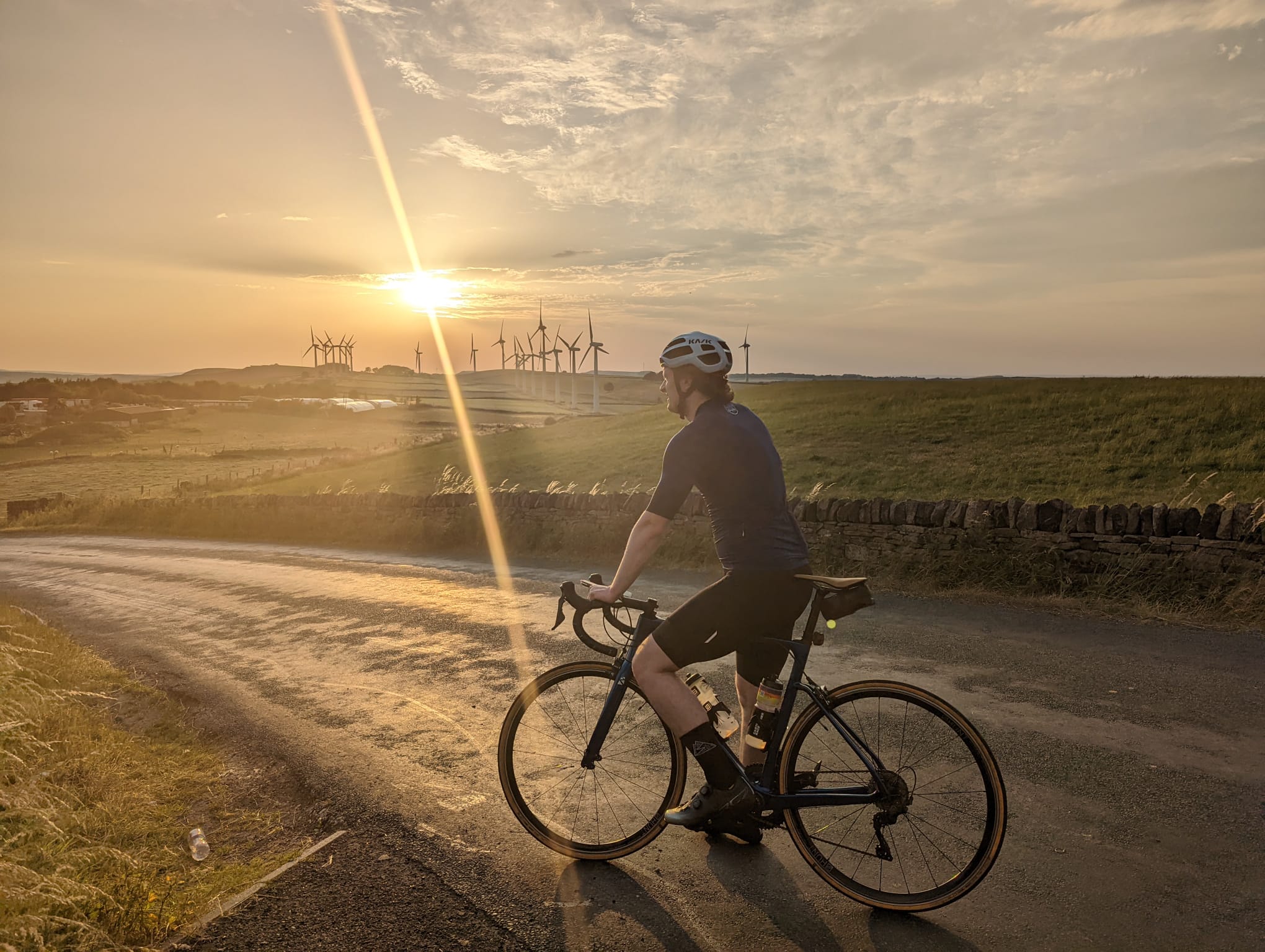 Shea cycling at sunset with wind turbines on the horizon