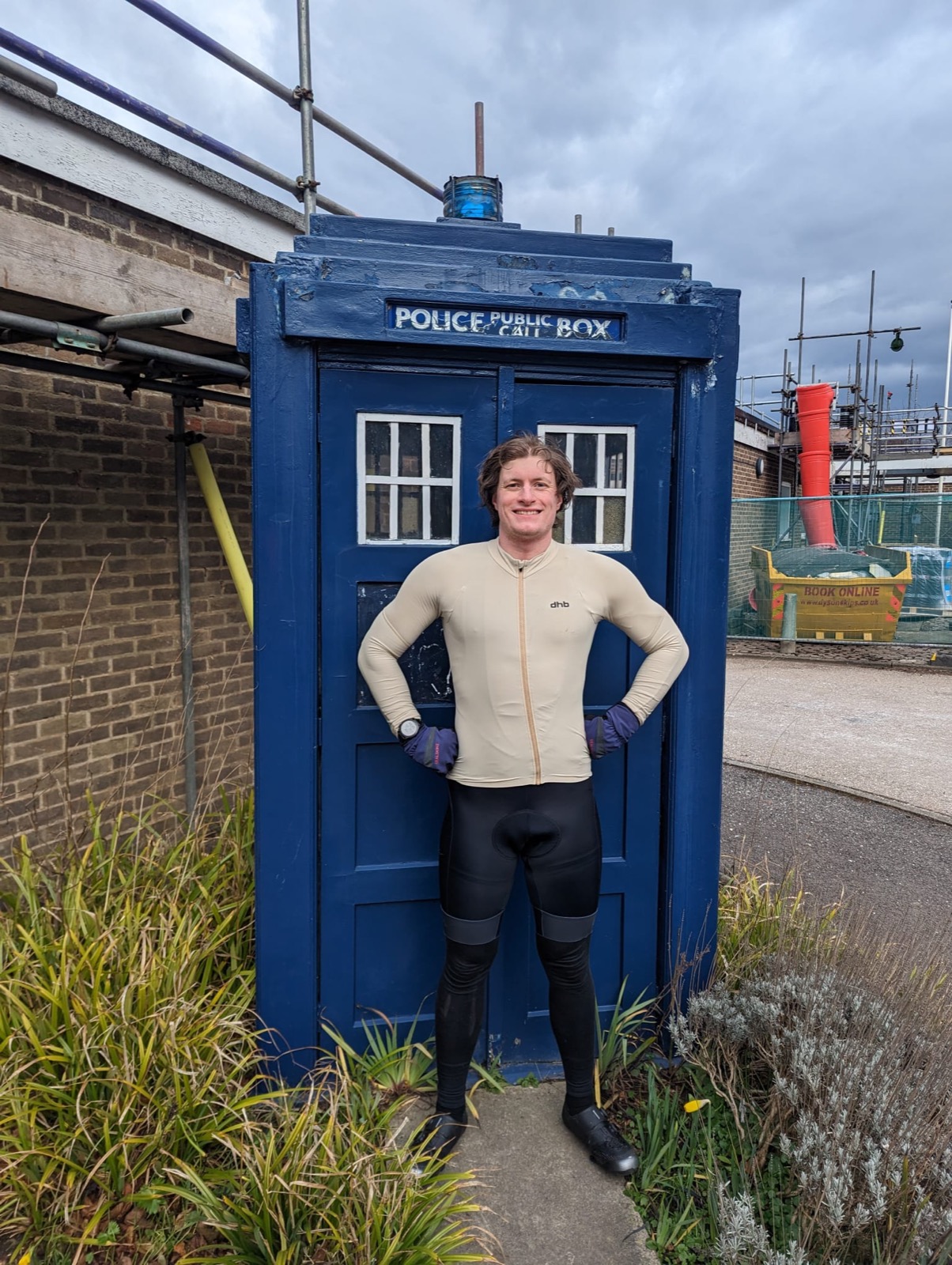 Shea standing in cycling kit in front of a blue police public call box